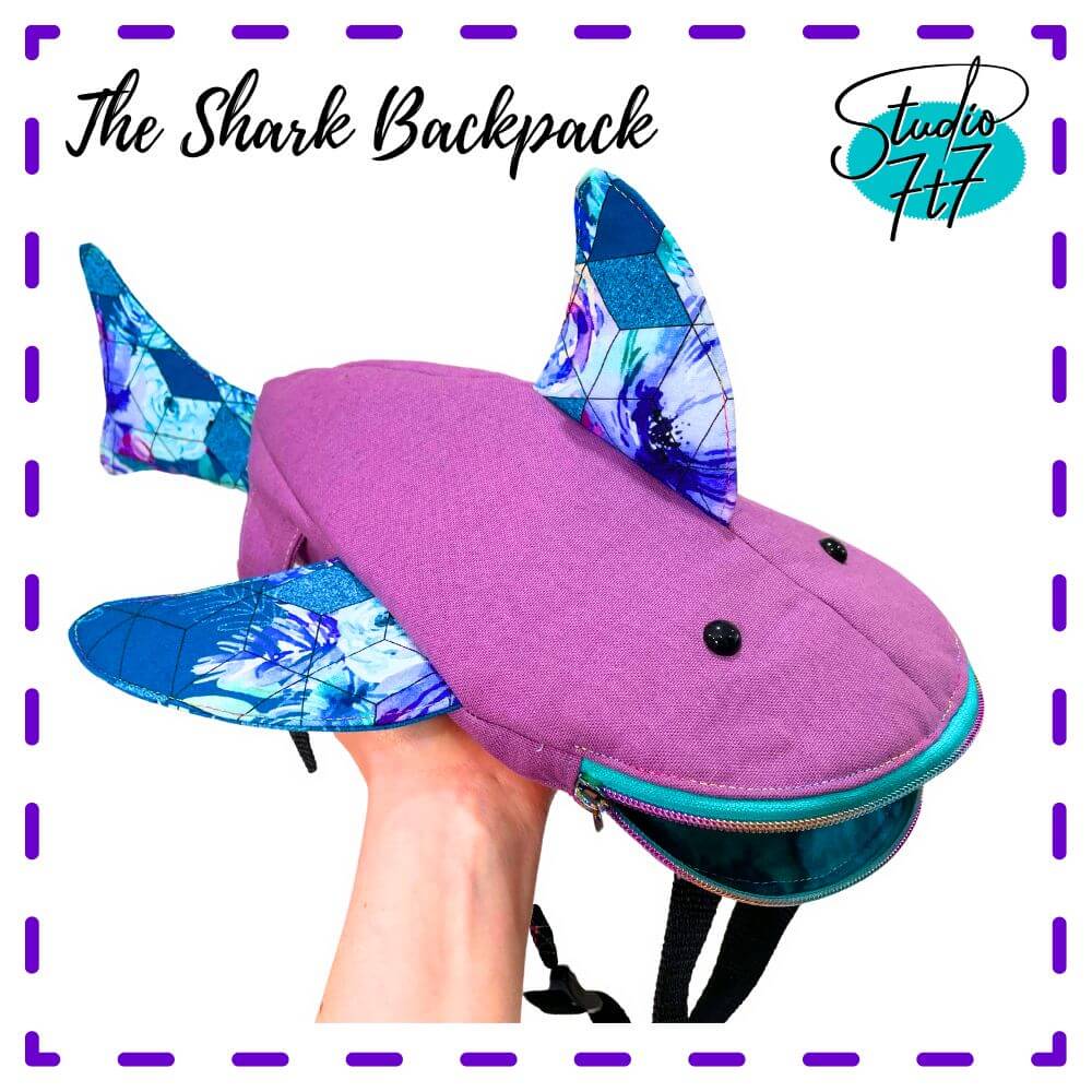 A photo of a shark shaped backpack held in a hand.